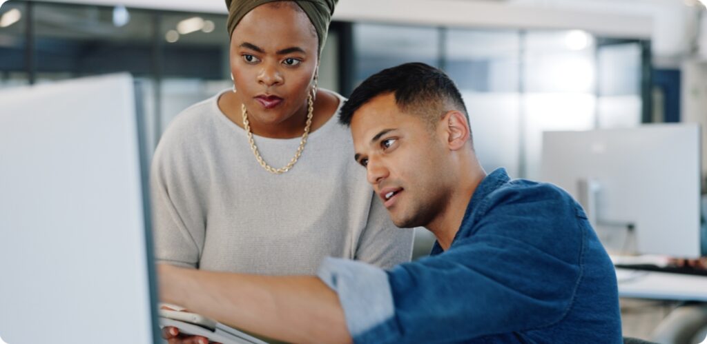 Um homem e uma mulher a apontar para dados num computador.